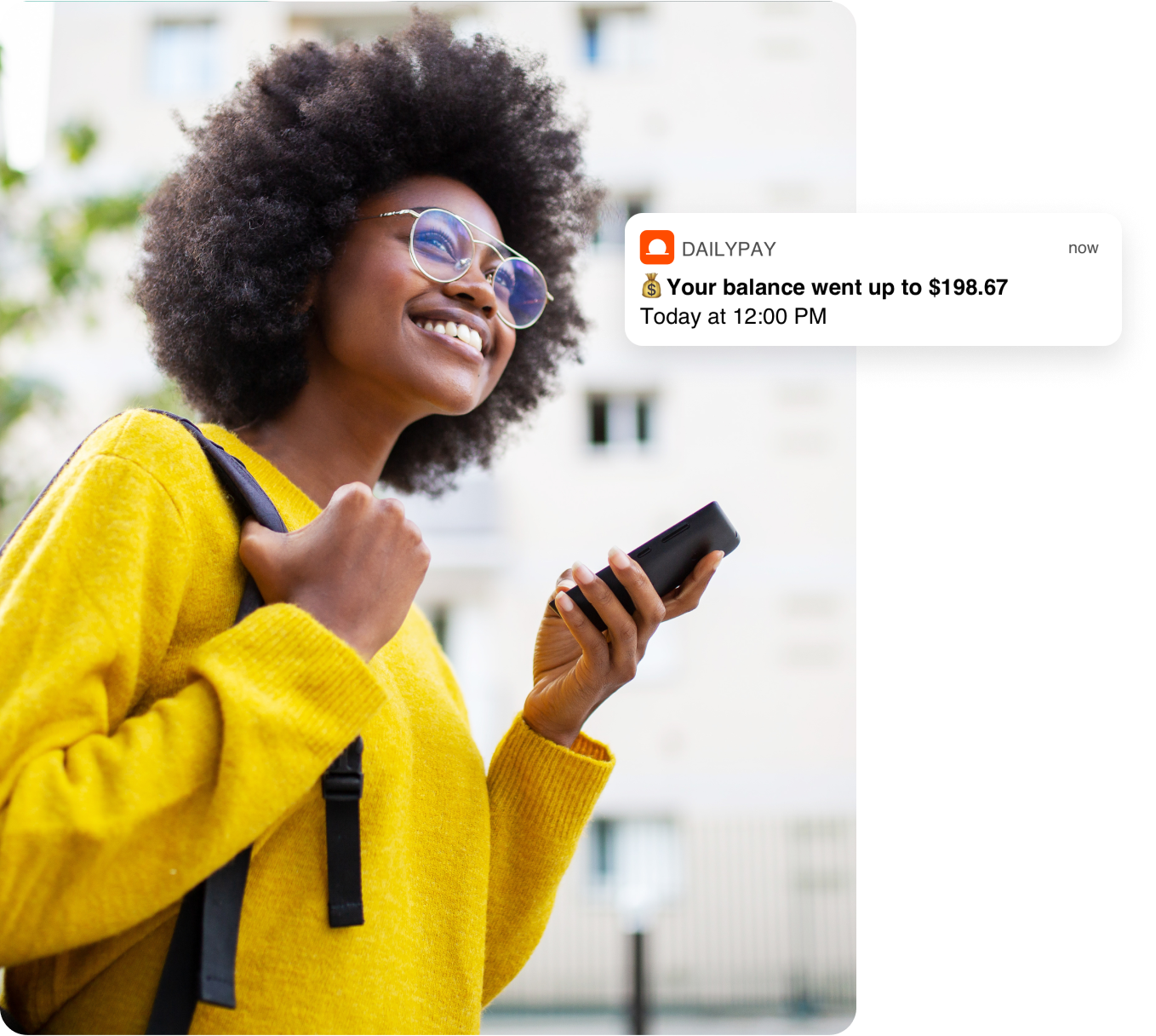 A person in a yellow sweater smiles while holding a phone. An on-screen notification indicates the balance increased to $198.67.